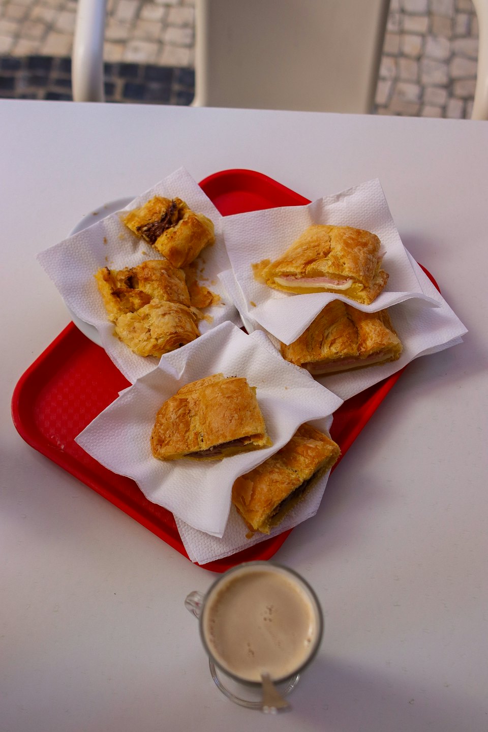 Golden-brown pastries and frothy coffee on a red tray.