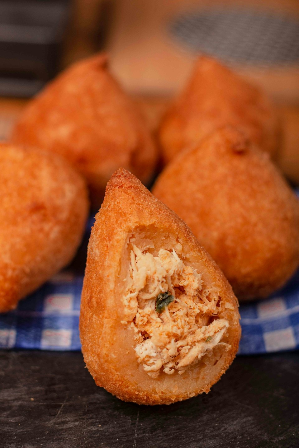 A golden fried coxinha split open revealing shredded chicken filling.