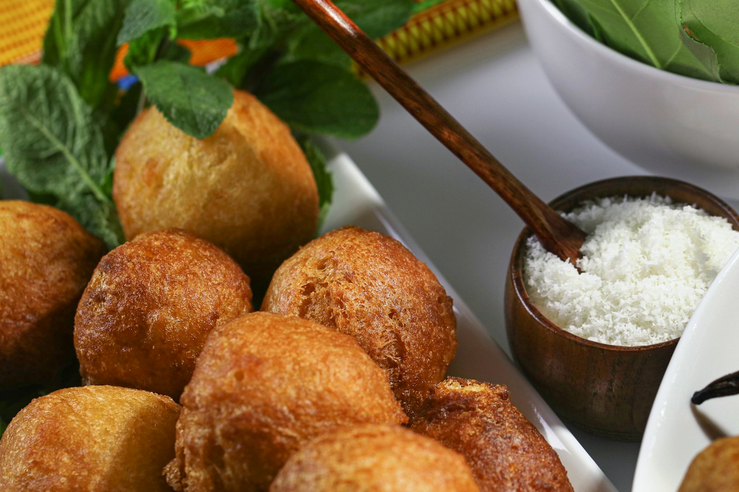 Golden fritters garnished with fresh mint leaves on a white dish.