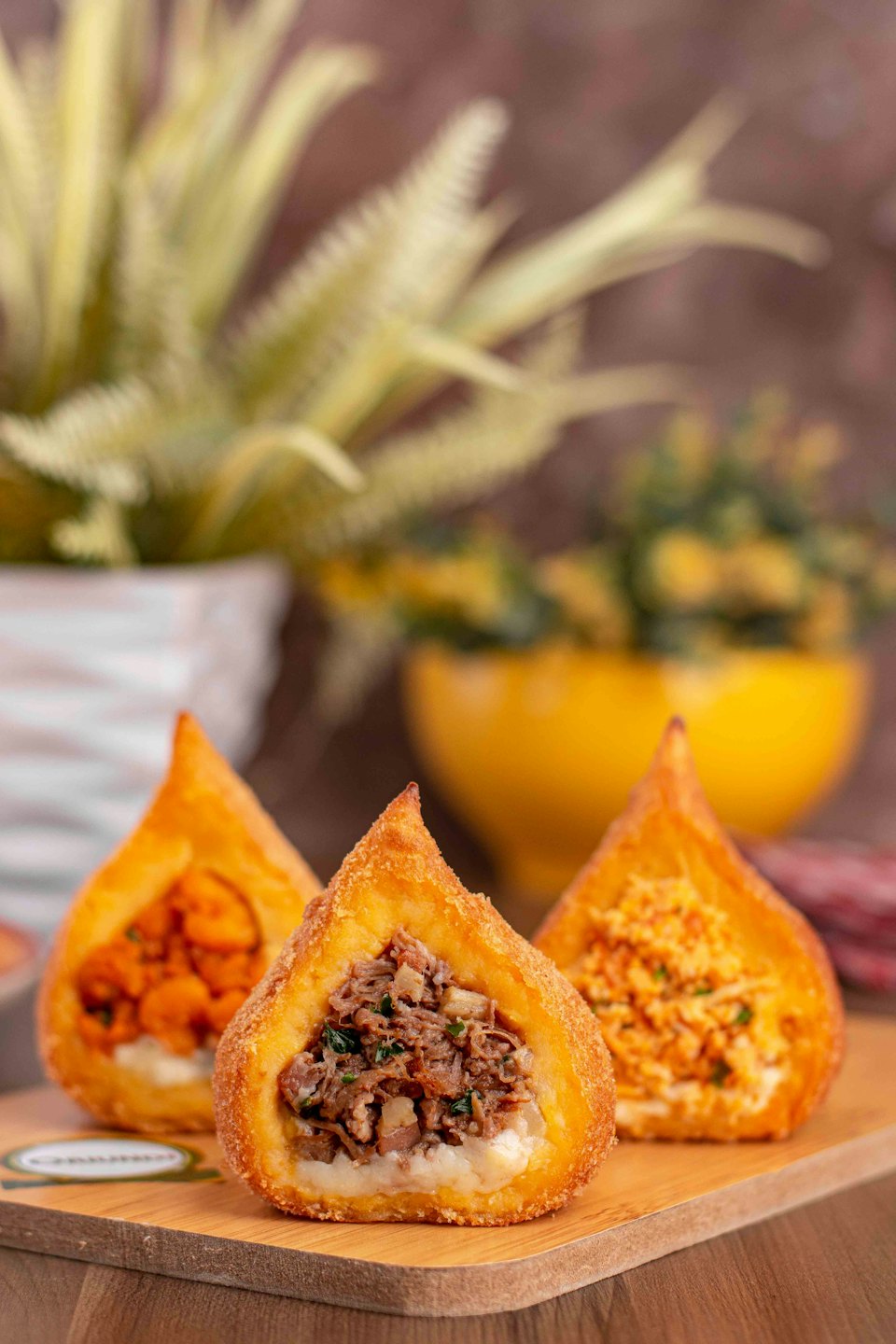 Three sliced chicken coxinhas arranged on a wooden cutting board.
